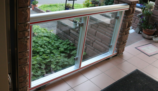 Dieses Terrassengeländer ist gefertigt aus Aluprofil 45x90, abgerundet durch zwei Profile 45 halbrund. Die offenen Profilnuten sind verschlossen mit Kunststoff-Abdeckprofil in rot und grau. Mittels Edelstahl Glasklemmen wurden 8mm Sicherheitsglasscheiben